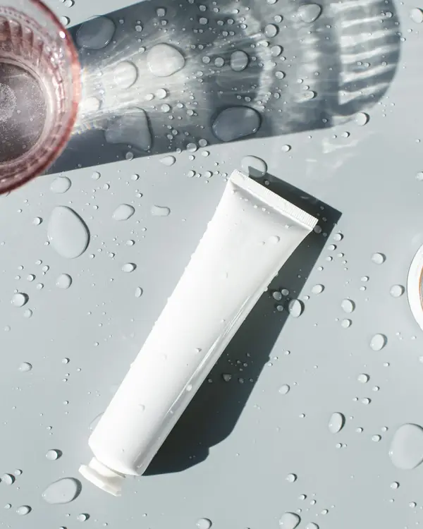 Tubo branco de gel de limpeza sobre superfície clara com gotas d'água
