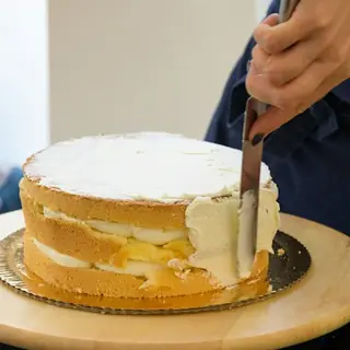 Bolo de camadas sendo coberto com creme