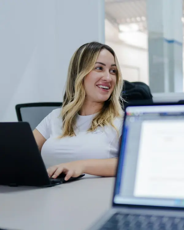 Aluna sorrindo enquanto assiste a uma aula no notebook