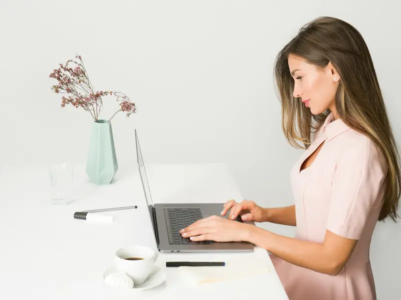 Mulher planejando posts no notebook em uma mesa branca