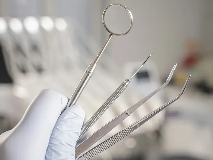 Mão com luva segura espelho, sonda e pinça