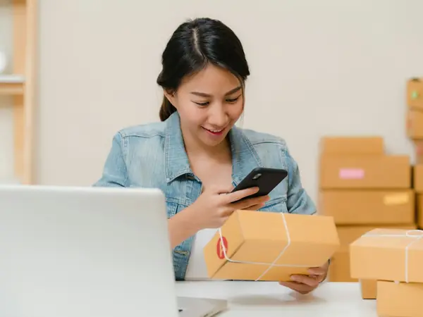 Empreendedora fotografa um pacote com o celular antes do envio