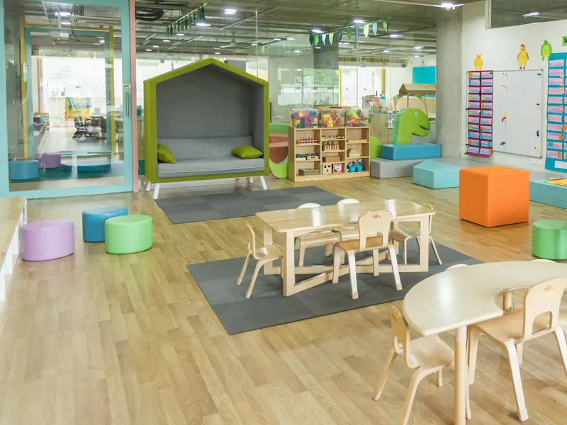 Sala ampla com mesinhas, pufes coloridos e cantinho de descanso