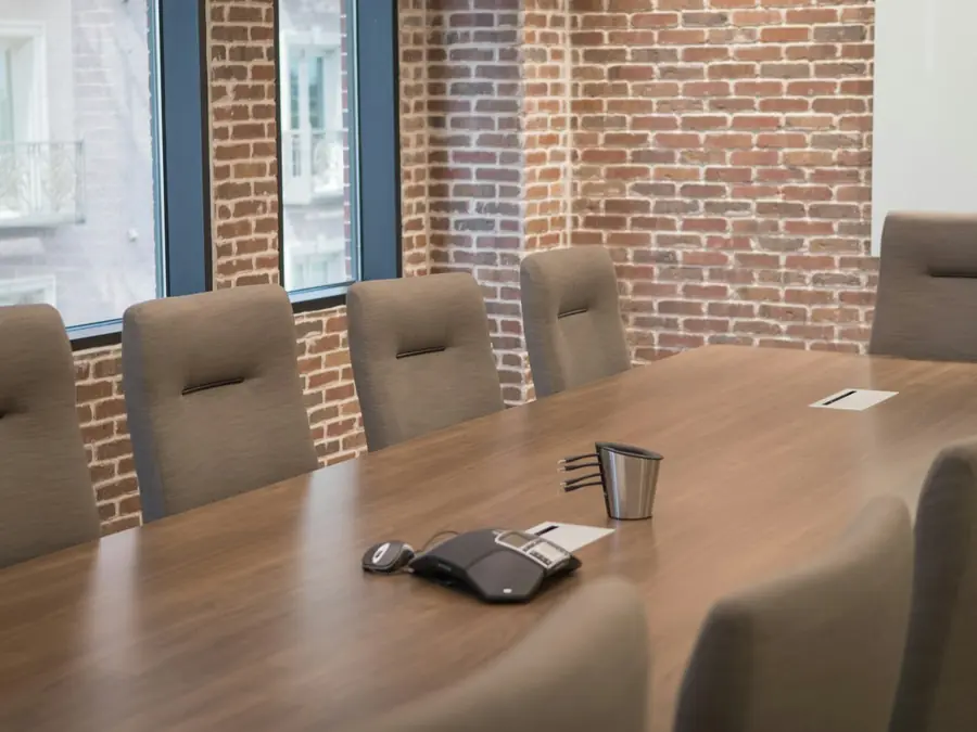 Sala de reuniões do escritório, com mesa de madeira e cadeiras